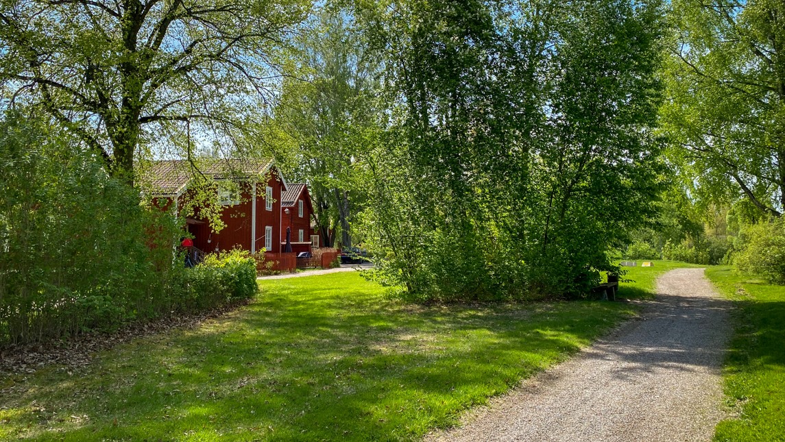 Promenadstig i grönska och några röda stugor.