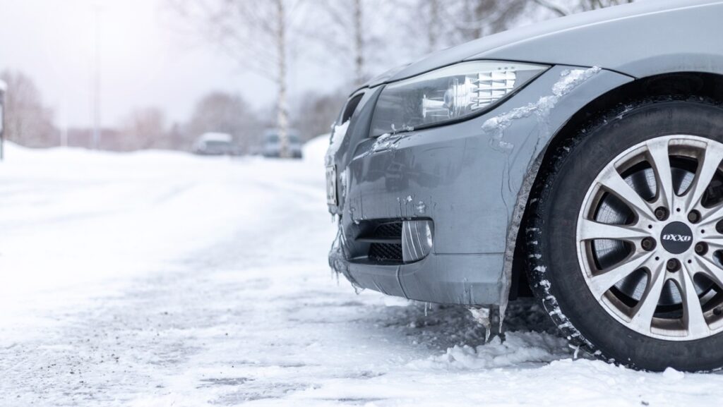 Parkerad bil på snöig parkeringsplats.