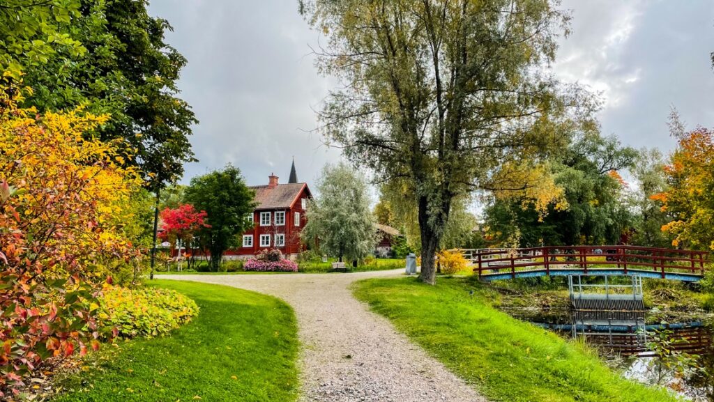 Naturen i höstens färger och rödmålat hus i bakgrunden.