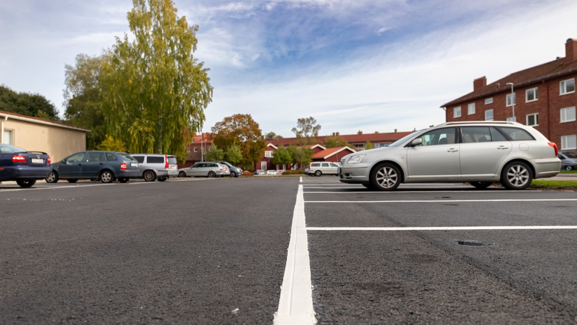 Nyasfalterad parkeringsplats och några bilar.