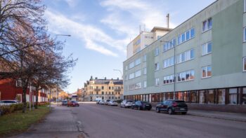 En stadsgata kantad av höga byggnader och parkerade bilar.